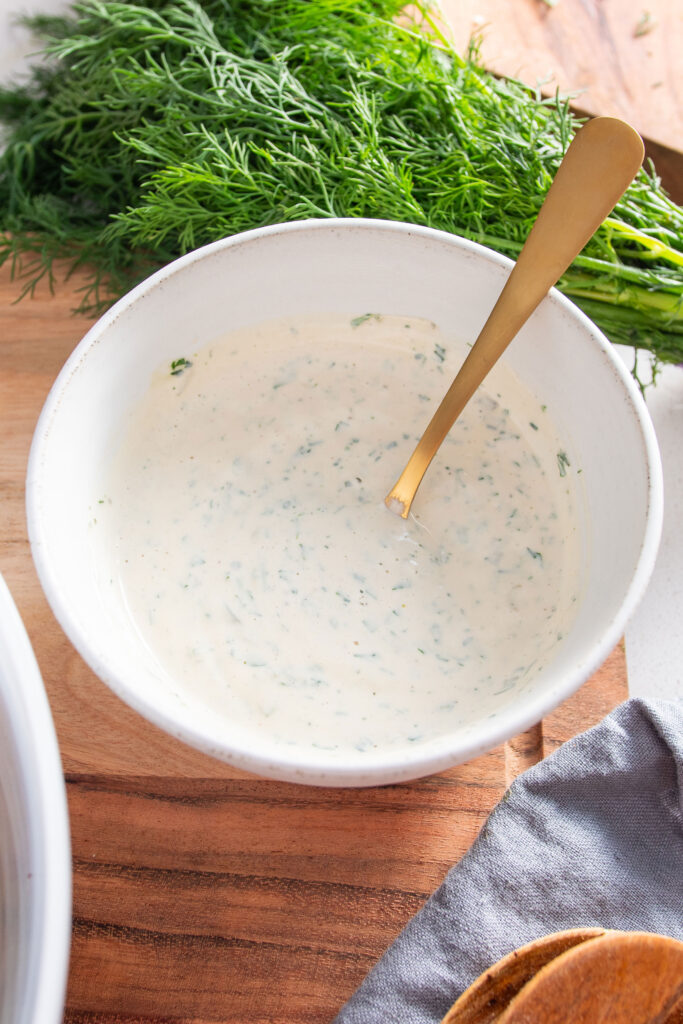 Healthy ranch dressing in a bowl with a gold spoon