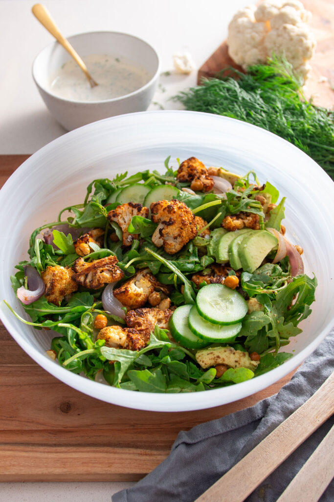 Large bowl with roasted cauliflower salad with drizzle of healthy ranch dressing