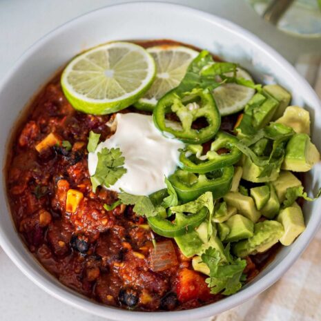 Image of a bowl of 3-bean chili with toppings. The image is appetizing and showcases a comforting and flavorful vegetarian chili option.