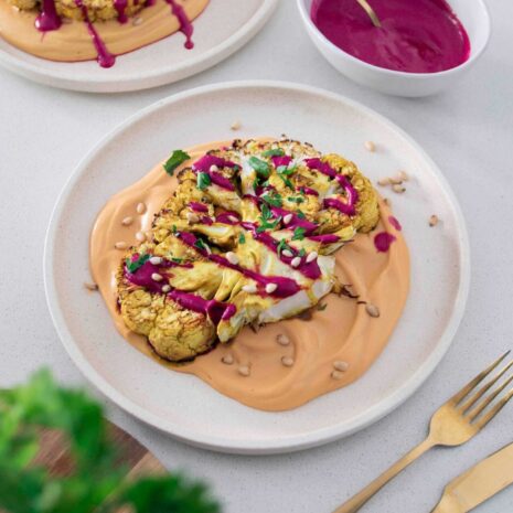 Sunset Cauliflower Steak - A mouthwatering vegan dish featuring a thick slice of roasted cauliflower, seasoned with aromatic spices and served with a vibrant sunset-colored sauce.
