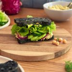 A mouthwatering chickpea-tuna sandwich with a creamy filling, topped with fresh lettuce and tomato slices, served on a toasted bun.