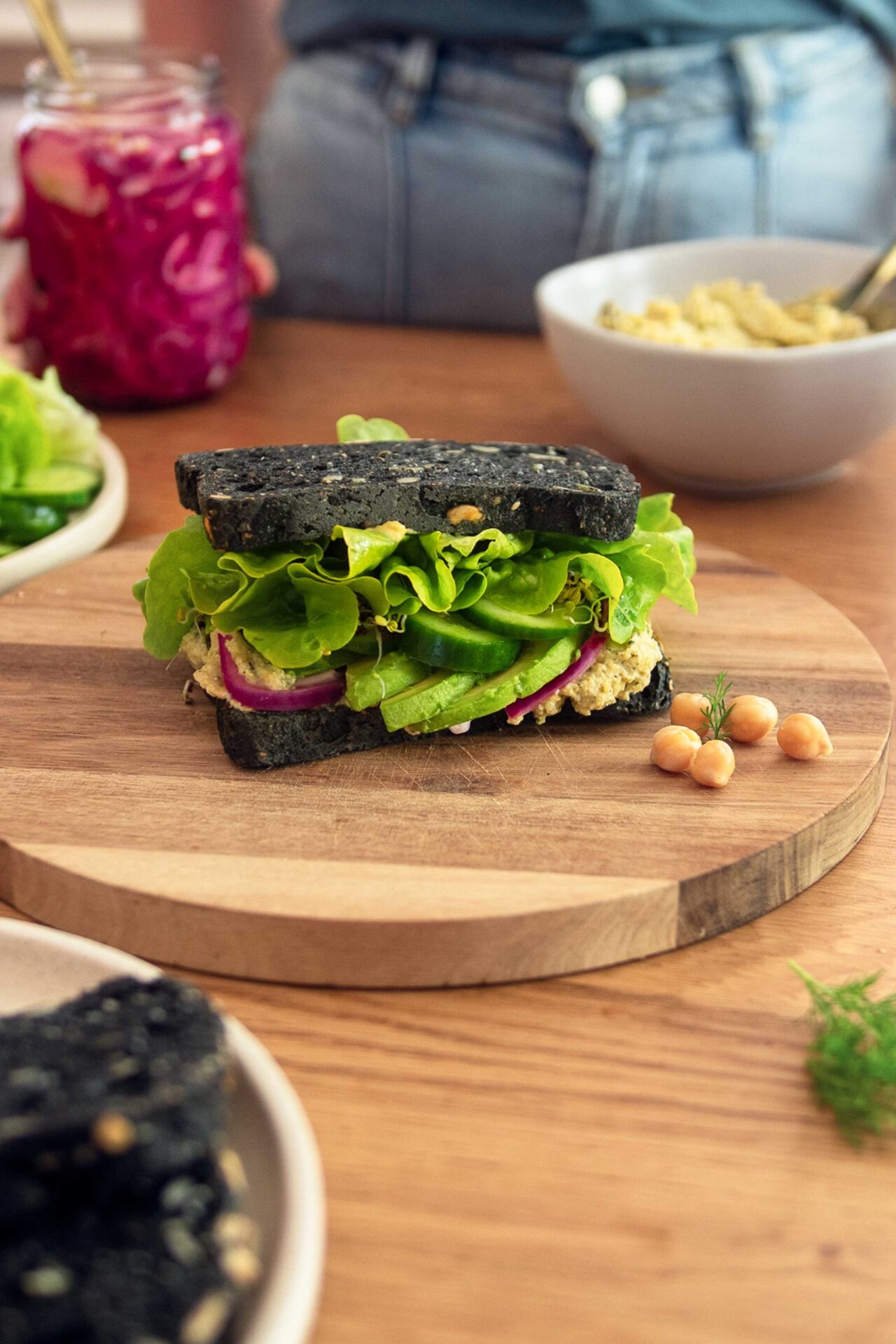 A mouthwatering chickpea-tuna sandwich with a creamy filling, topped with fresh lettuce and tomato slices, served on a toasted bun.