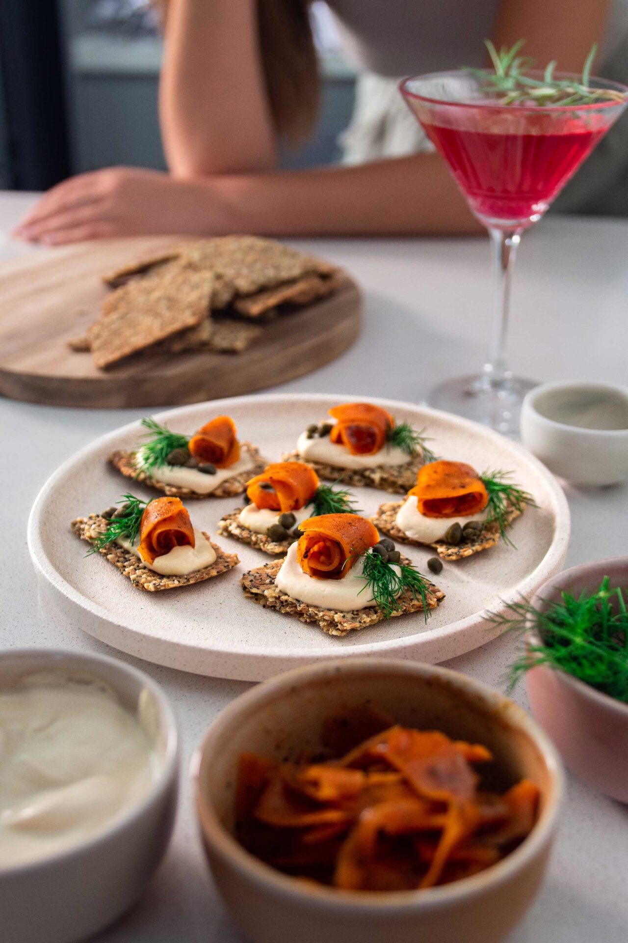 Vegan cream cheese carrot lox canapés arranged on a platter, topped with fresh dill and served with crackers.