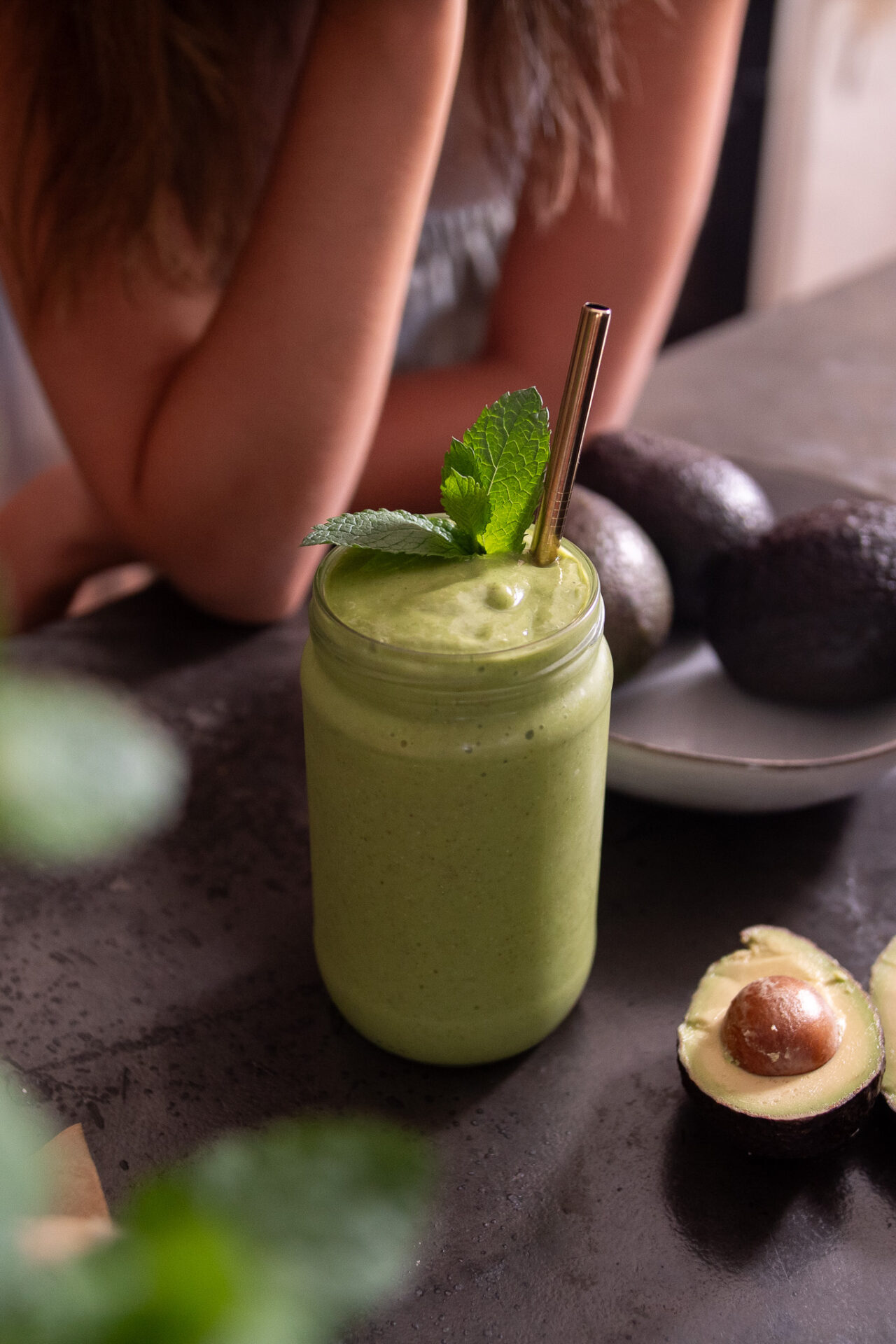 Vibrant, green creamy avocado smoothie, surrounded by avocados