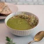 Vibrant green, creamy, broccoli, soup covered in sprouts