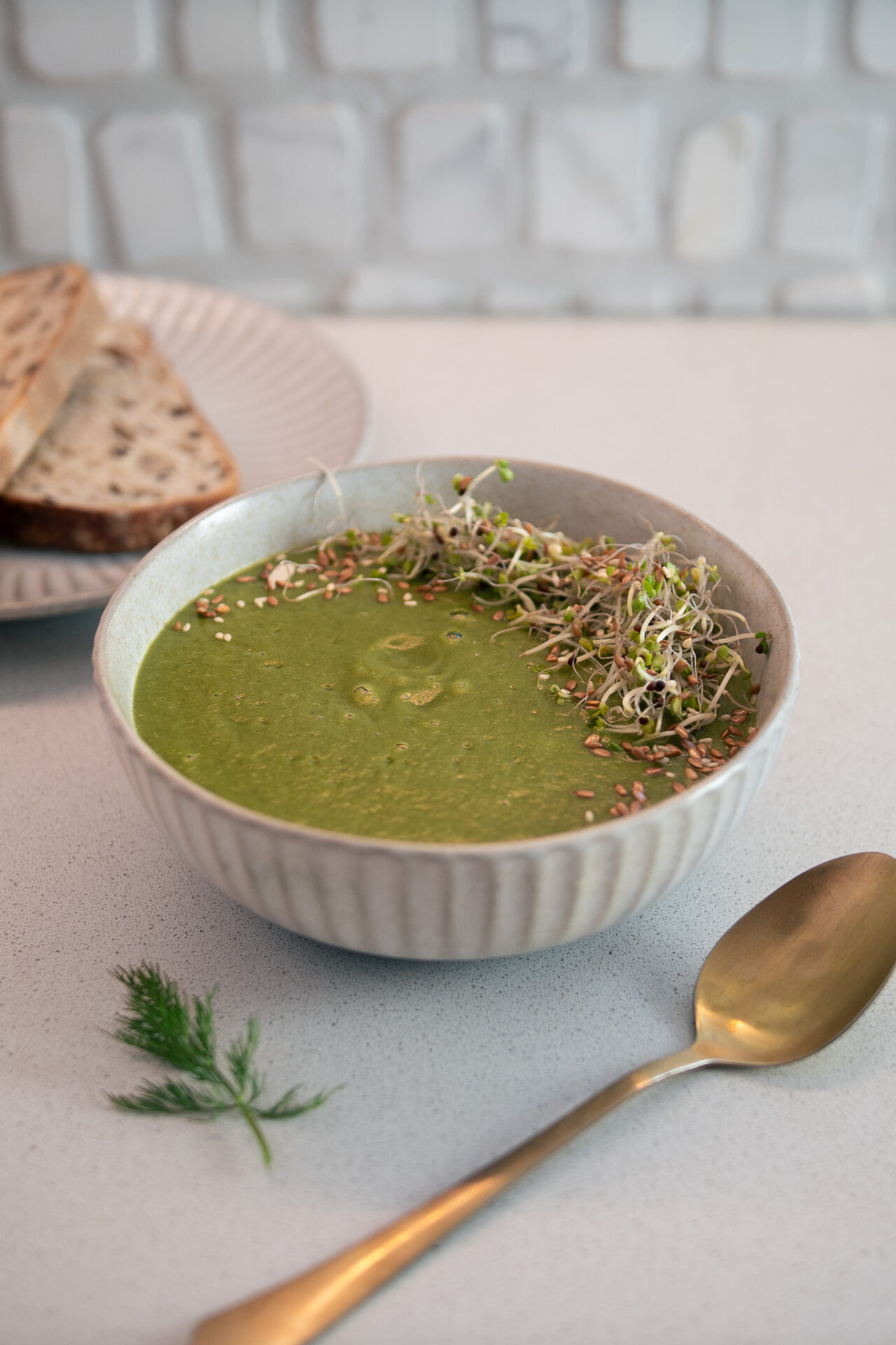 Vibrant green, creamy, broccoli, soup covered in sprouts