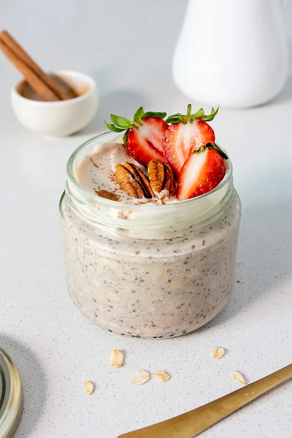A festive overnight oats jar with gingerbread flavoured oats, topped with greek yogurt, cinnamon, pecans and strawberries