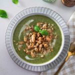 A bowl of rustic green goddess soup, garnished with fresh herbs