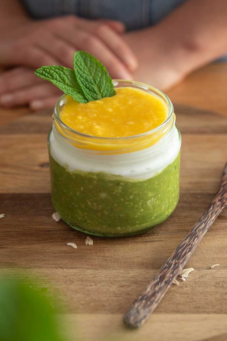 A jar of matcha overnight oats topped with fresh mint