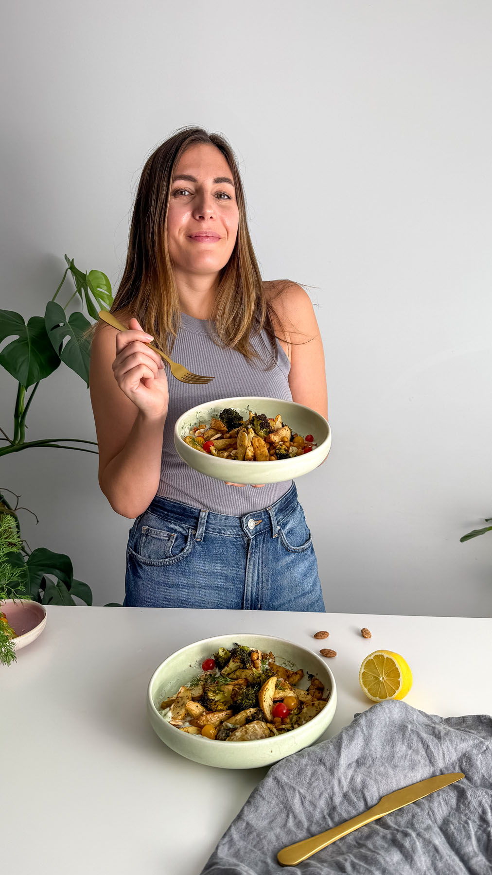 Sarah Cobacho in front of a kitchen island holding a Mediterranean Tzatziki Bowl, ready to eat.