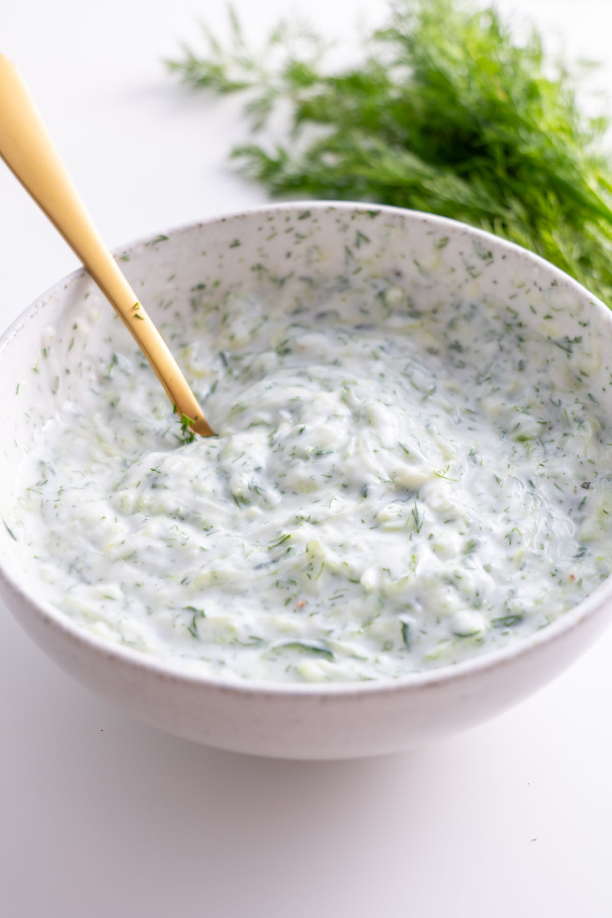 Freshly mixed tzatziki sauce with dill in a bowl.