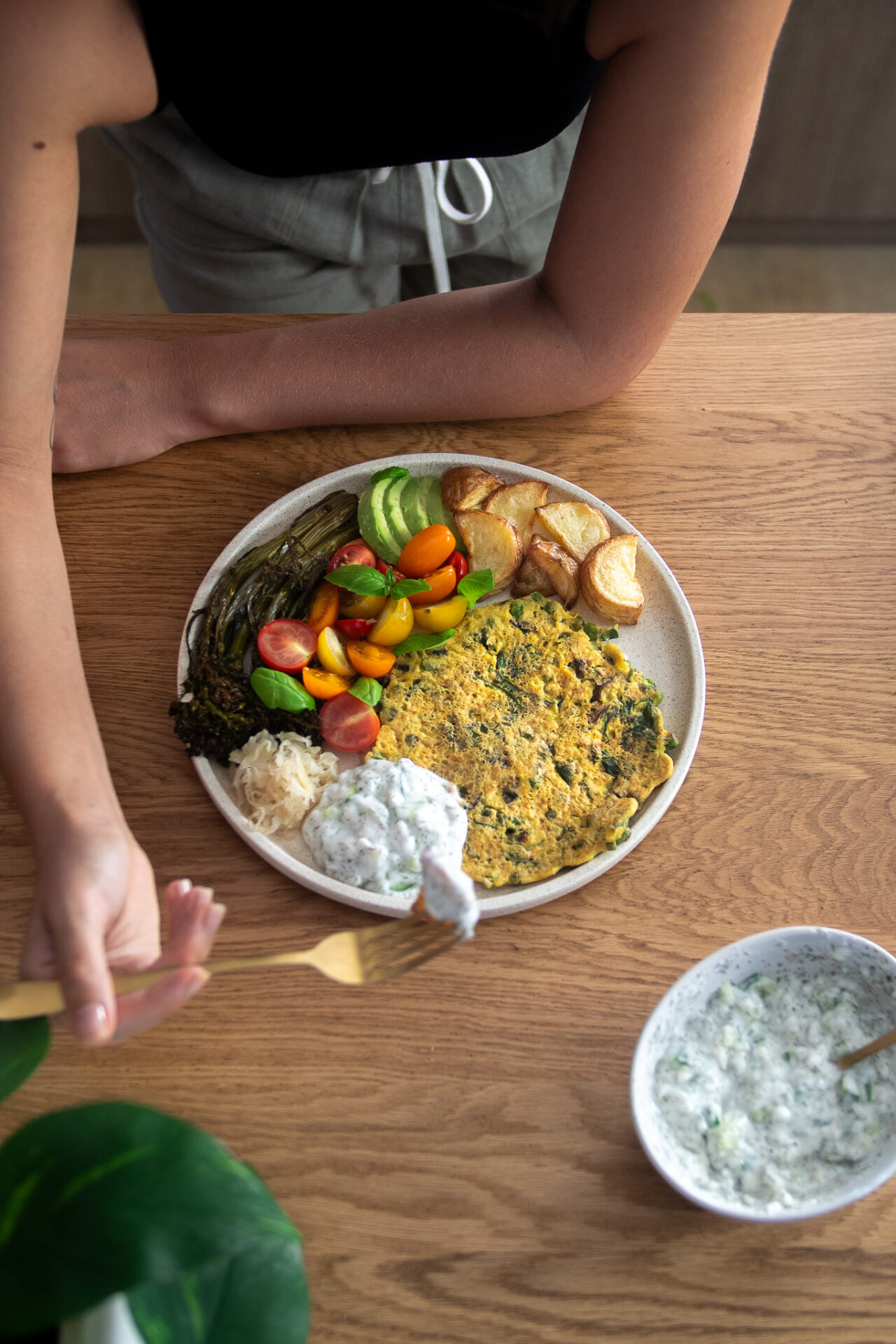 Vibrant plate, full of potatoes, veggies, and a plant-based omelette