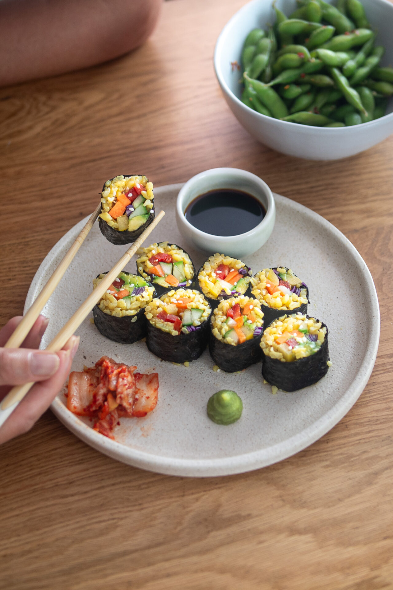 Plant-based rainbow sushi rolls on a plate with chopsticks
