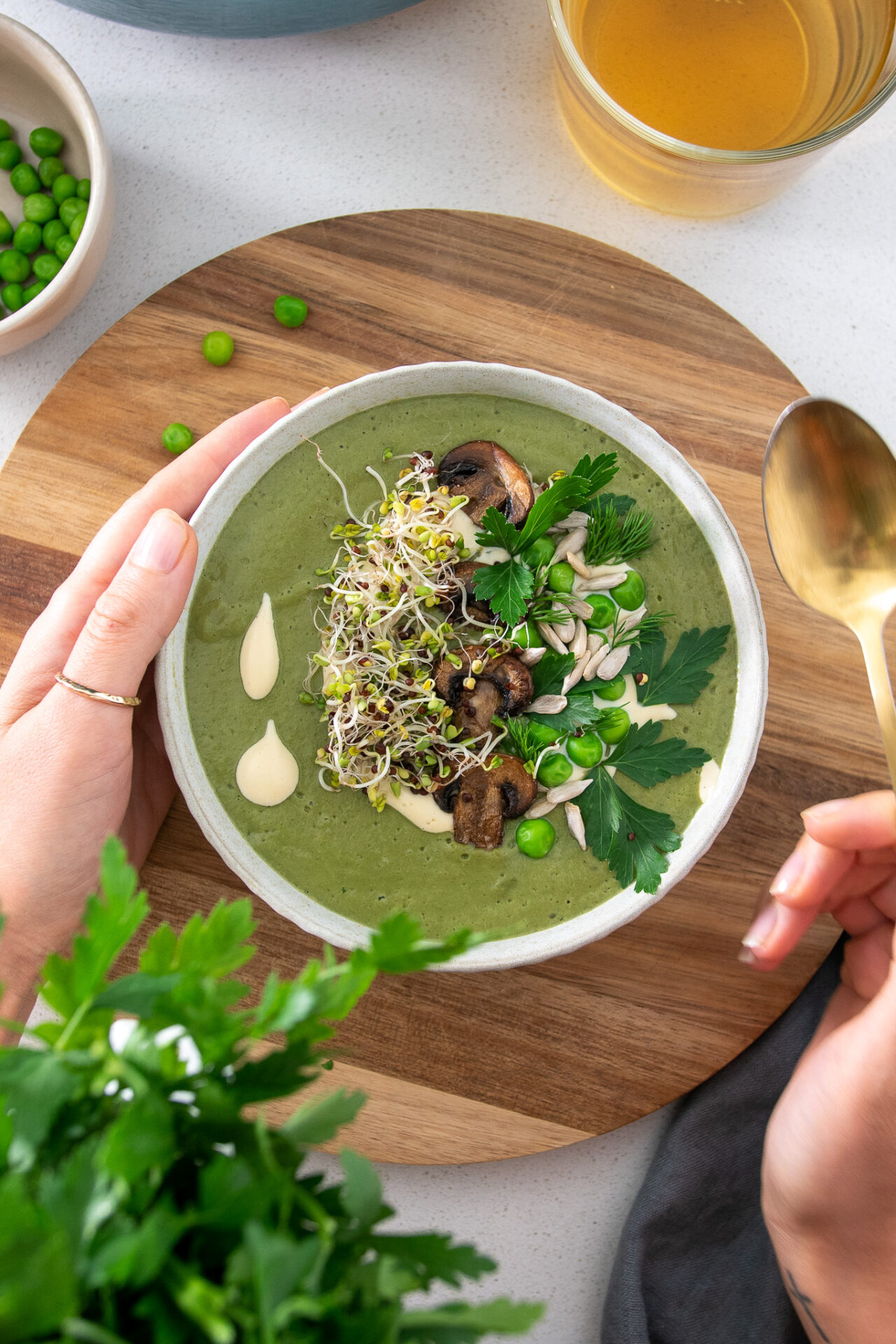 Vibrant green soup with sprouts and other herbs on a wooden serving board
