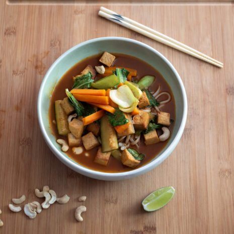 Bowl of spicy red curry noodle soup with chopsticks