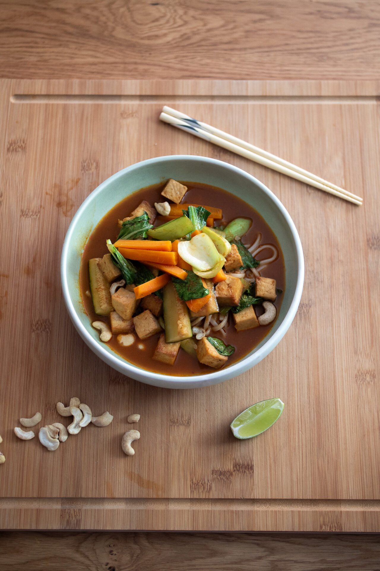 Bowl of spicy red curry noodle soup with chopsticks