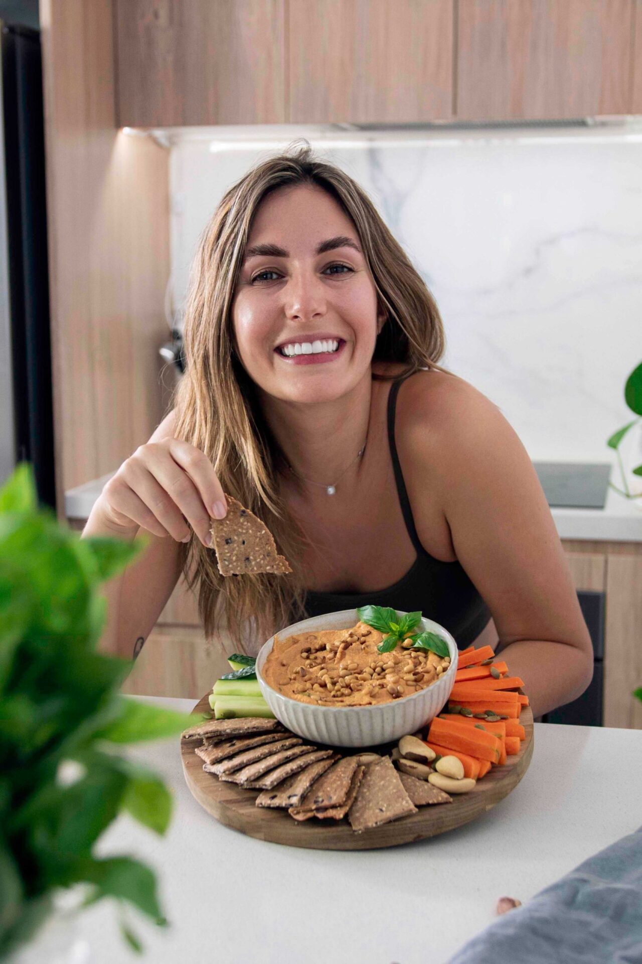 Mediterranean sun-dried tomato dip served in a bowl with crackers and fresh vegetables.