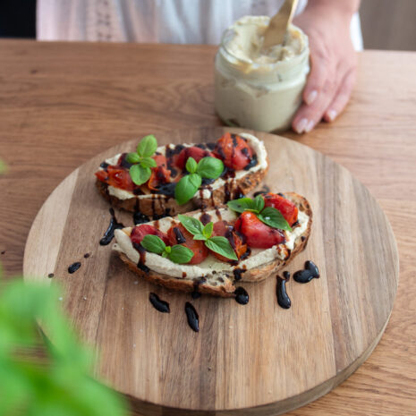 Sourdough with tofu, cream cheese, spread and tomatoes on a wooden serving board