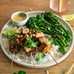 Tofu satay skewers on a bed of rice with broccolini