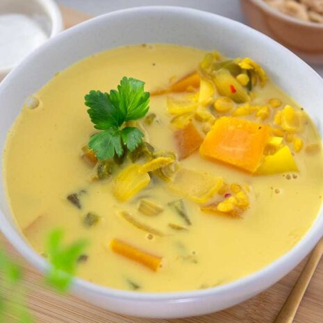 A bowl of warm and comforting turmeric lentil soup, garnished with fresh herbs.