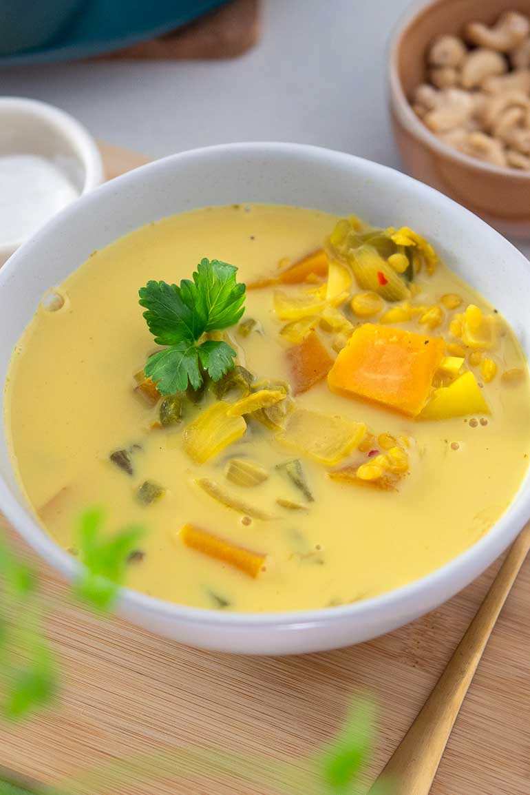 A bowl of warm and comforting turmeric lentil soup, garnished with fresh herbs.