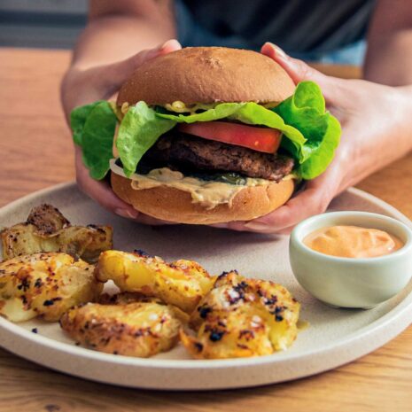 Mouthwatering vegan burger with a juicy plant-based patty, topped with fresh lettuce, ripe tomatoes, and creamy vegan mayo