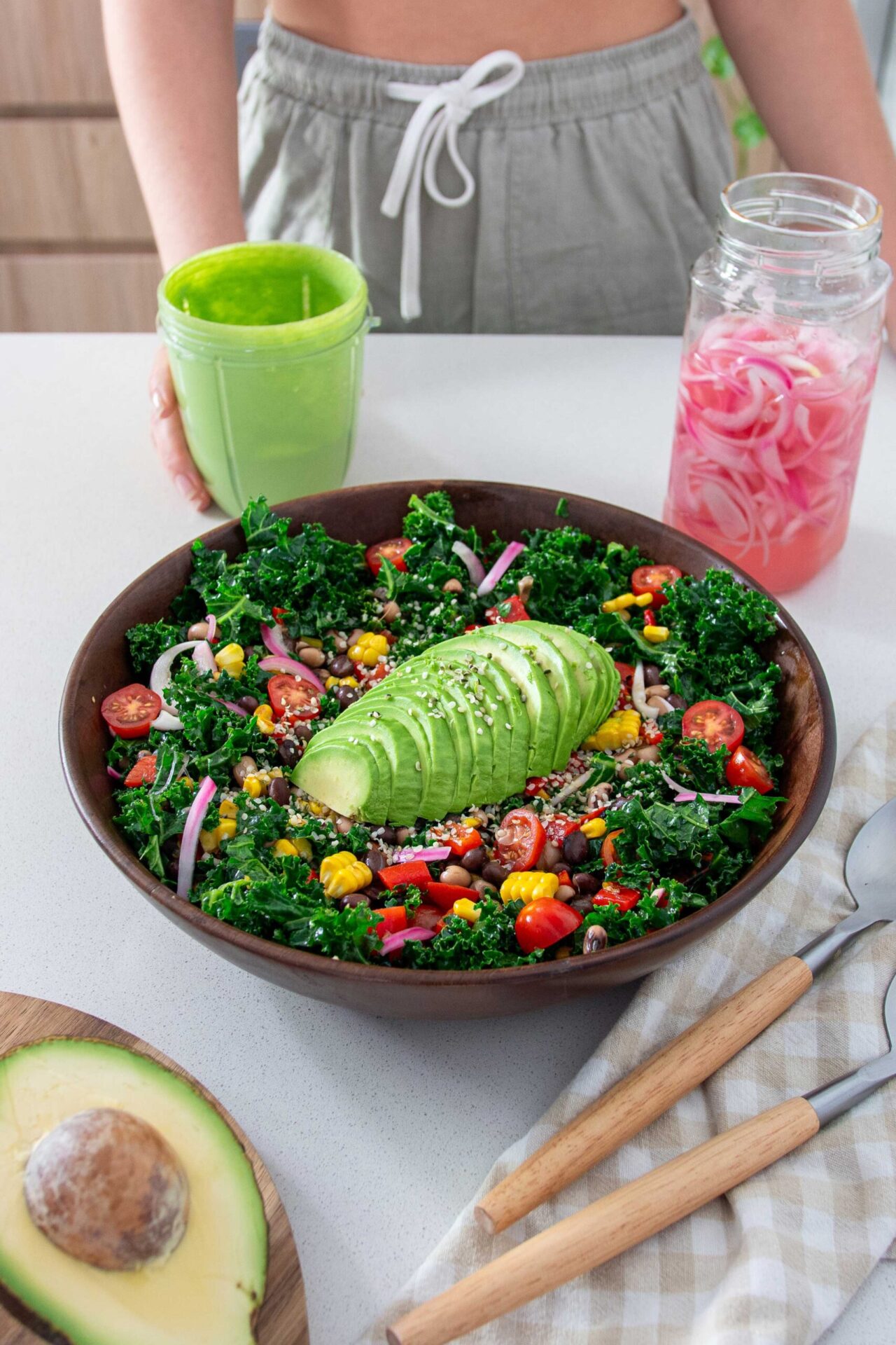 2-Bean avocado salad in a big wooden salad bowl with a jar of vibrant green dressing