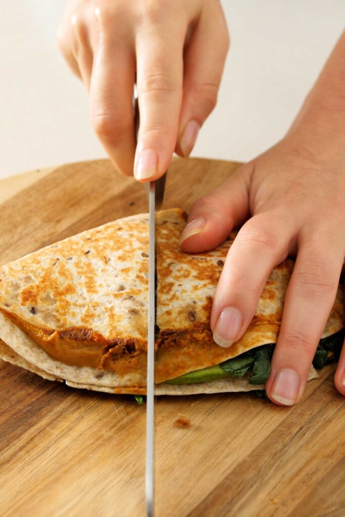 Cutting into the crispy looking avocado tortilla wrap with a bread knife