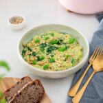 A bowl of vibrant green butter bean pesto with buckwheat bread on the side
