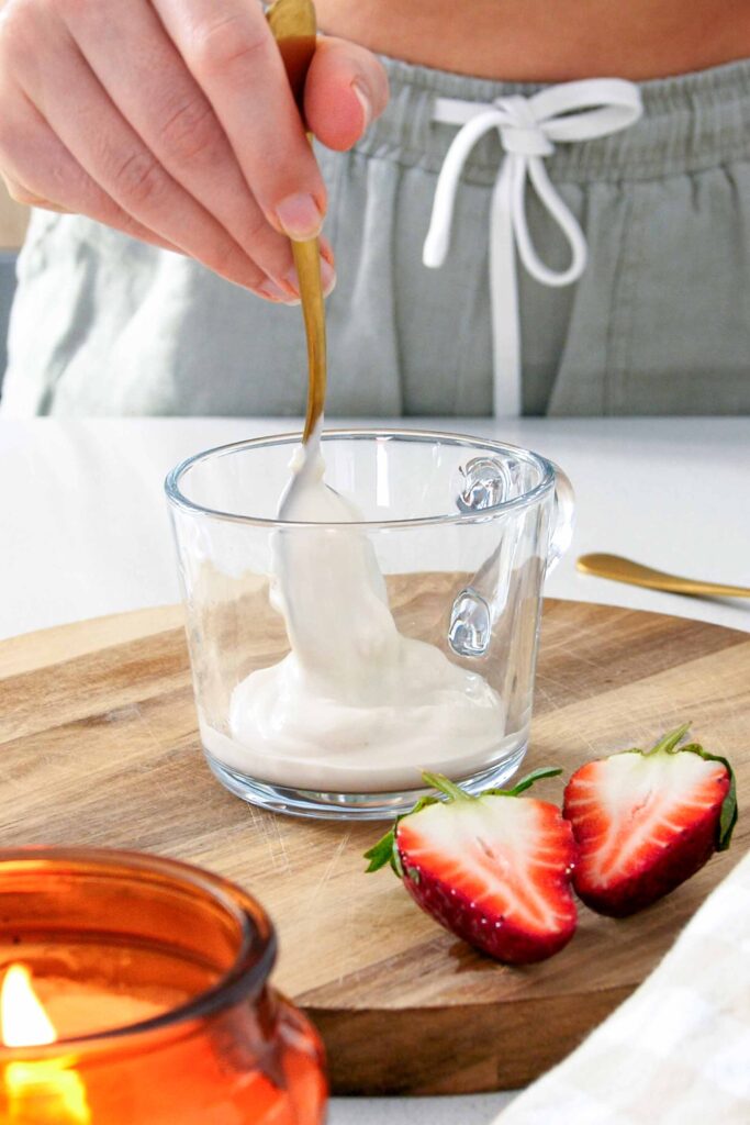 Golden spoon layering yoghurt into the bottom of a glass