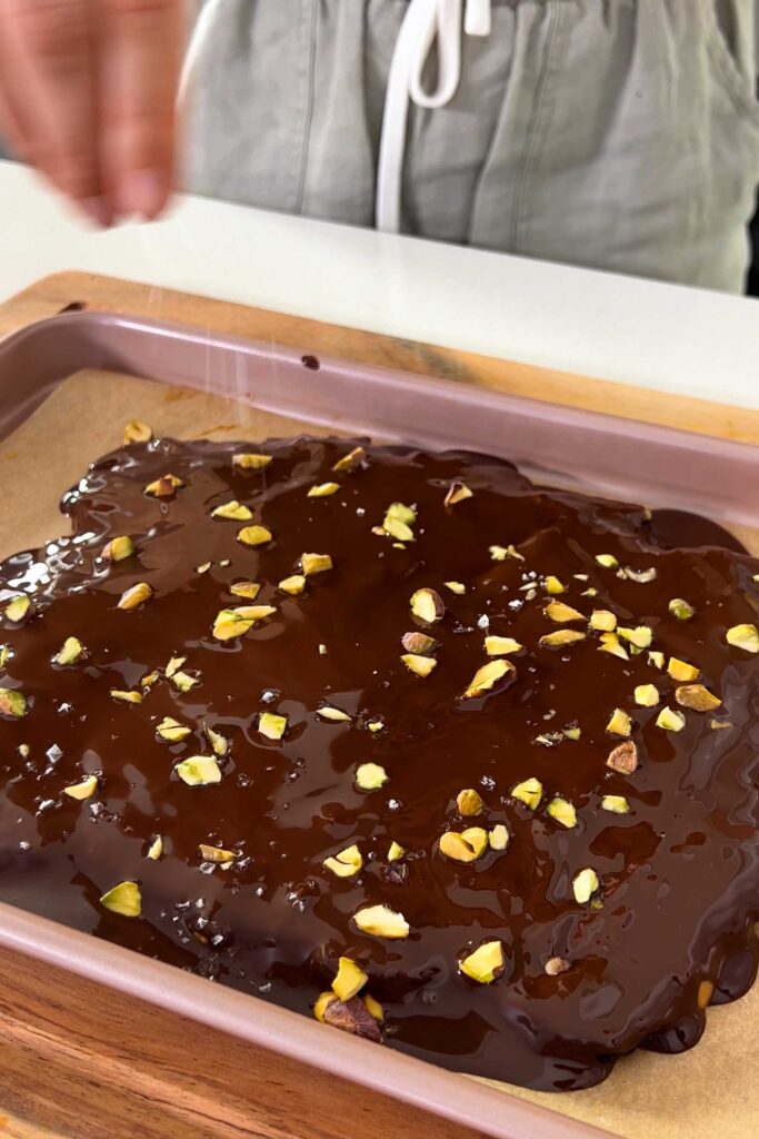 Topping the Medjool date bark, peanut butter and melted chocolate, and chopped pistachios with sea salt.