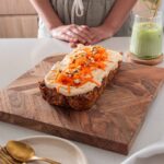 Baked Oats Carrot Cake on a wooden serving board alongside plate with spoon and fork