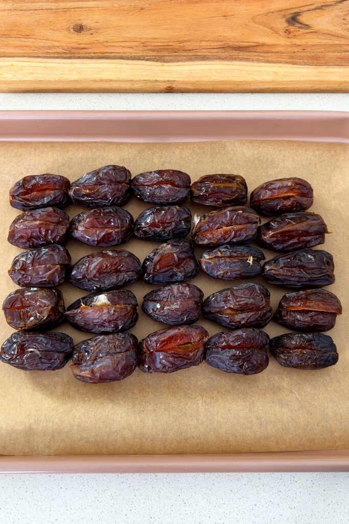 Medjool Dates laid out in a rectangular shape on a baking tray