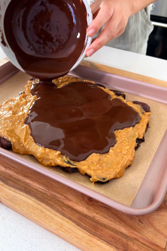 Coating the date and peanut butter with melted chocolate from a bowl
