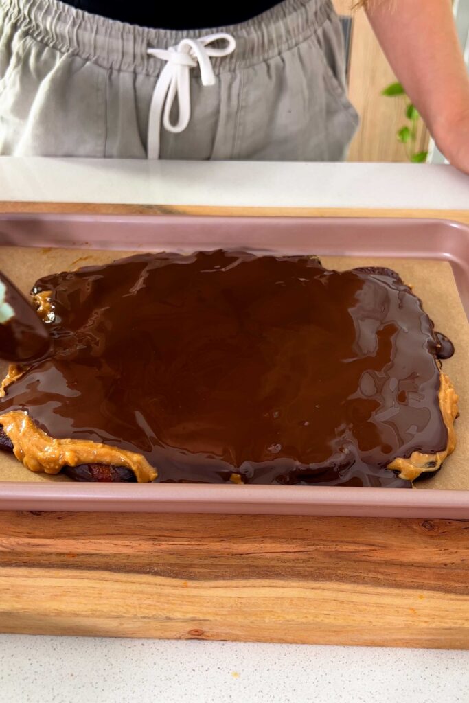Spreading the melted dark chocolate over the dates and peanut butter with a silicone spatula