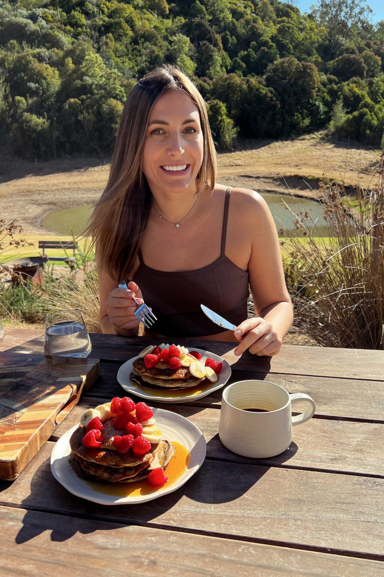 Sarah Cobacho of plantbaes at a bench in nature eating vibrant colored pancakes