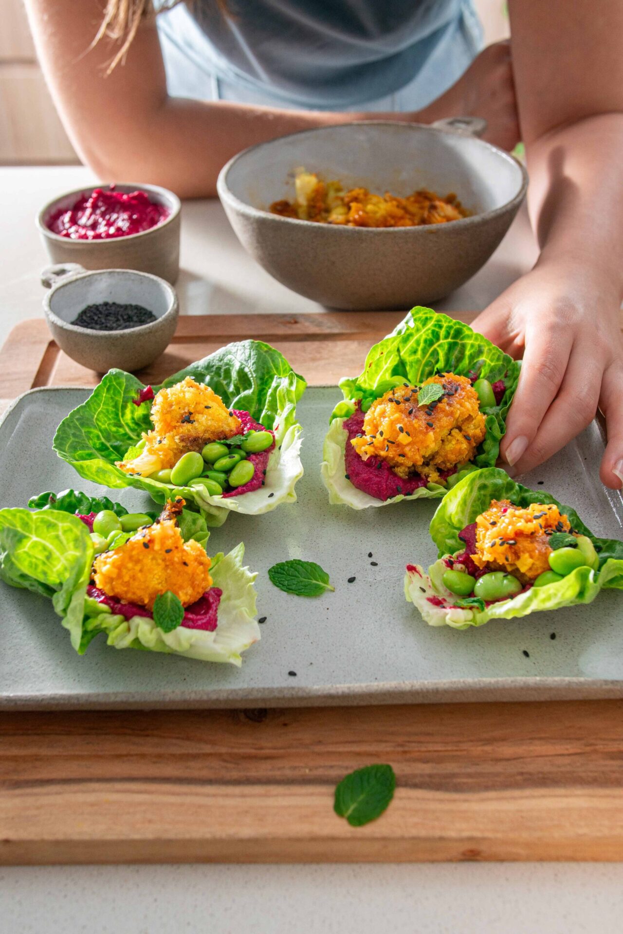 Crispy cauliflower wings on a bed of beetroot hummus, lettuce leaves on a serving platter