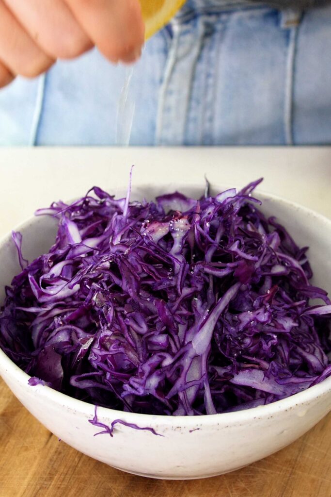 Creating the zesty cabbage slaw by mixing with lemon juice