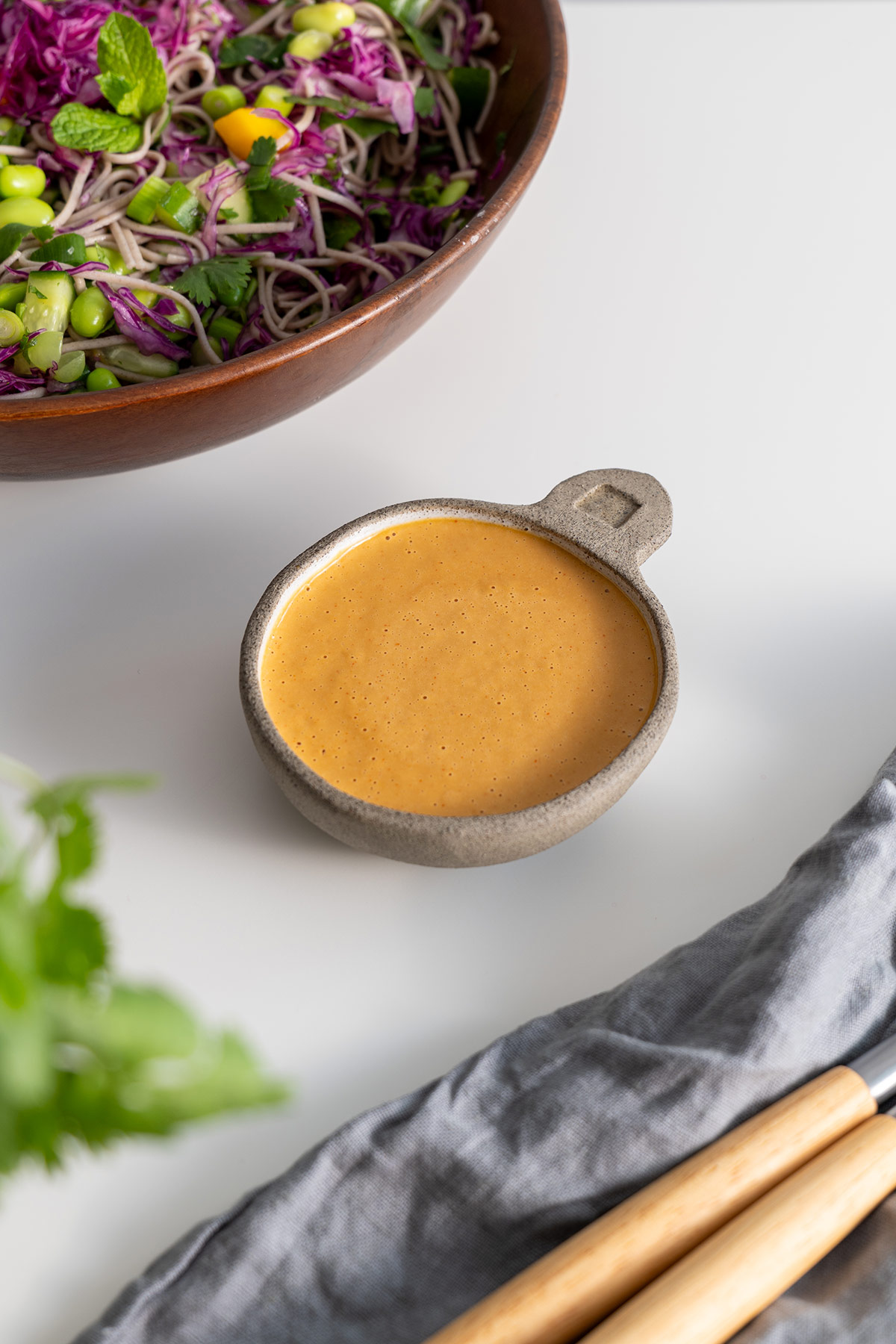 Smooth and spicy peanut sauce in a small stone bowl next to the Soba Noodle Salad.