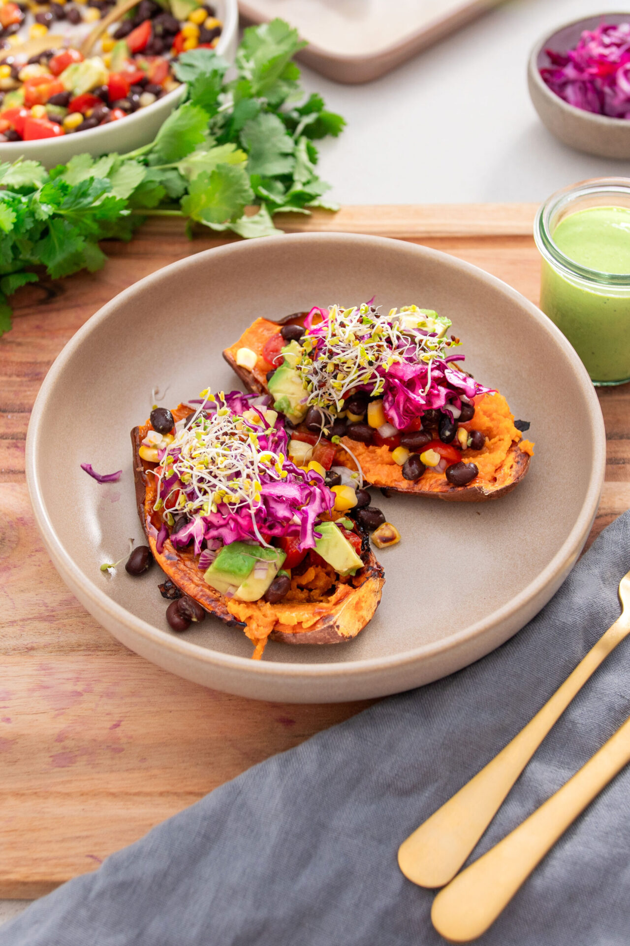 A bowl with vibrant, colorful roasted sweet potatoes topped with beans, veggies, cabbage slaw and sprouts