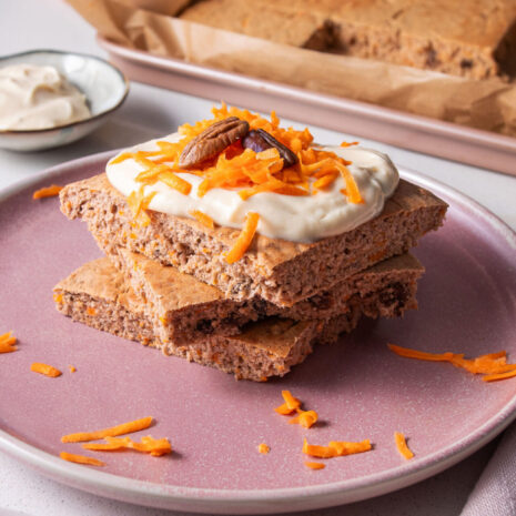 Stack of square sheet pan Carrot Cake Pancakes with yogurt icing and shredded carrot