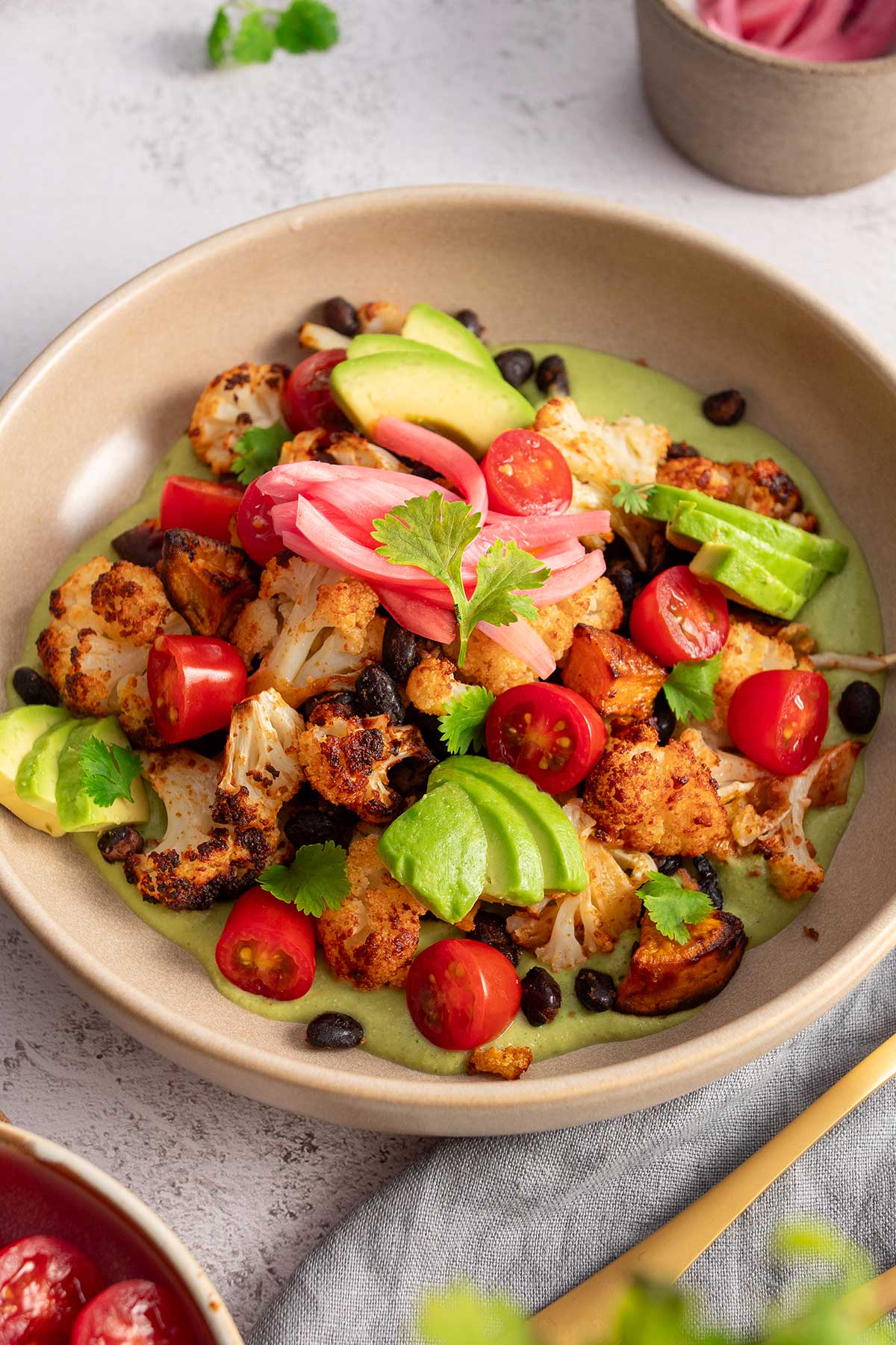 Close-up of a hearty, plant-based meal of roasted sweet potato and cauliflower with creamy cilantro sauce, perfect for a healthy lunch or dinner.