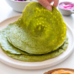 Image of a hand picking up a fresh, green buckwheat spinach wrap, showcasing its flexibility and texture.