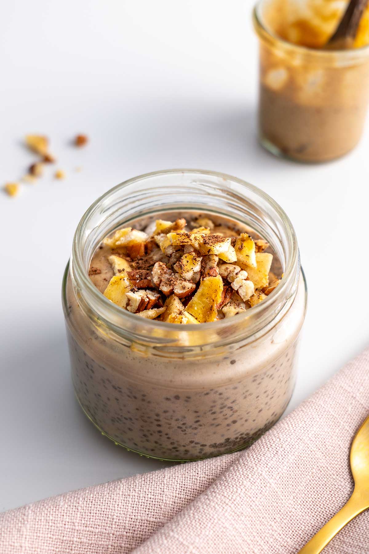 Close-up of creamy Banoffee Chia Pudding in a jar, topped with golden brown dehydrated bananas and a dusting of cacao, showcasing the layers and texture.
