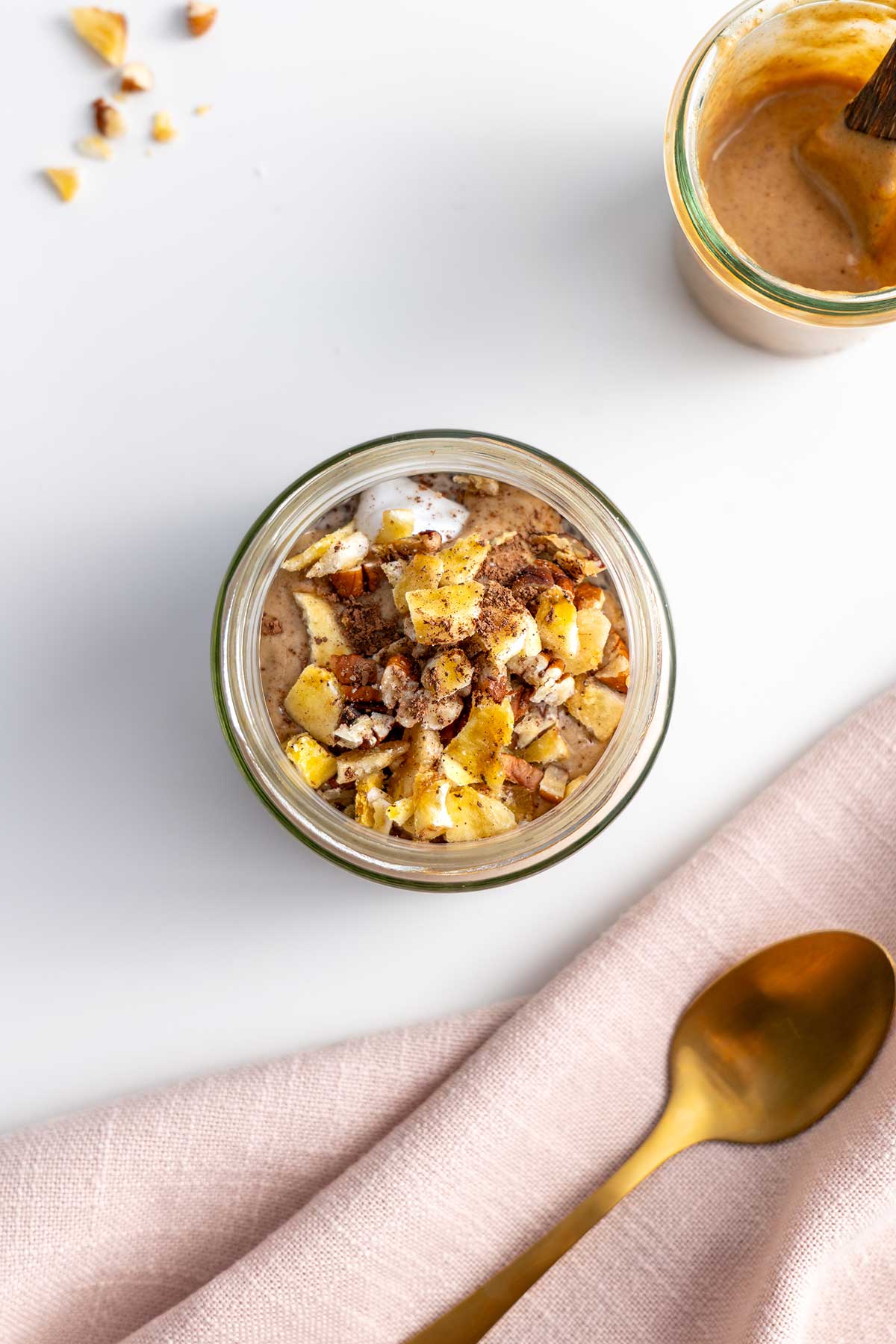 A top-down view of Banoffee Chia Pudding in a clear jar, garnished with chopped pecans and banana, ready to be enjoyed.