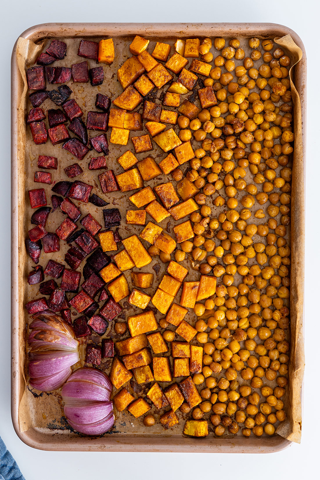 Baked butternut squash, beetroot, and chickpeas on a baking sheet for salad.