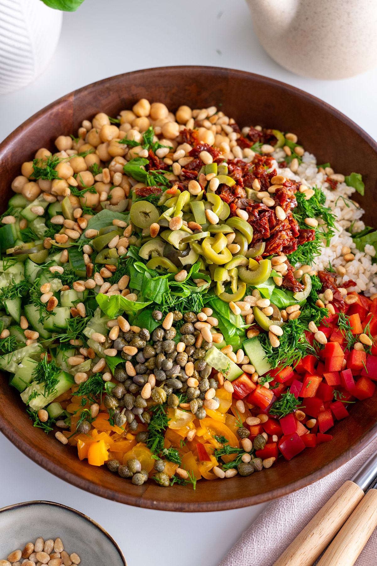 Overhead view of a colorful Mediterranean chopped salad in a wooden bowl, ready to be tossed.