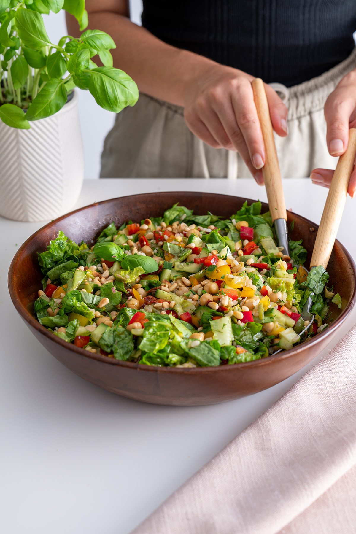 Mediterranean chopped salad in a wooden bowl, ingredients freshly tossed.