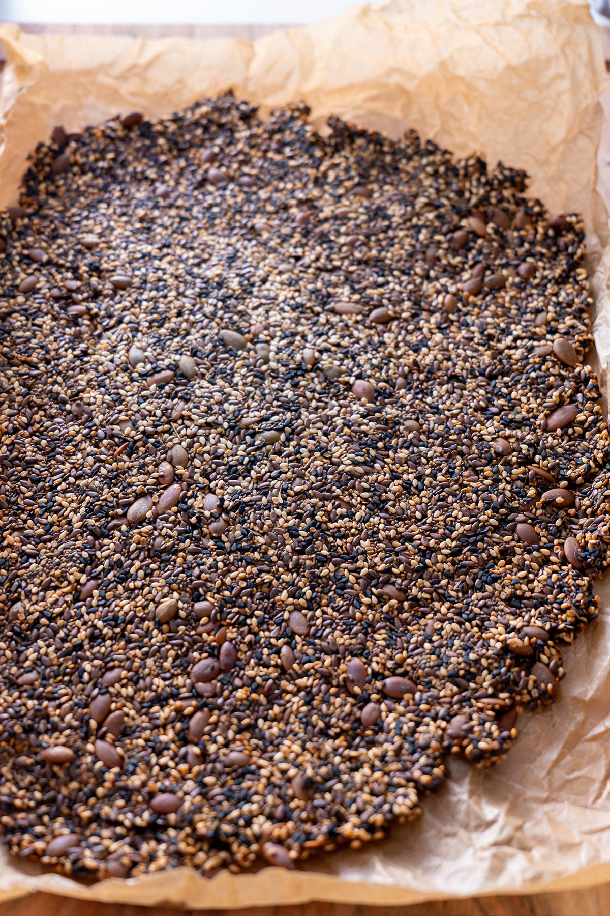Baked sheet of oil-free, flour-free seeded crackers on parchment paper.