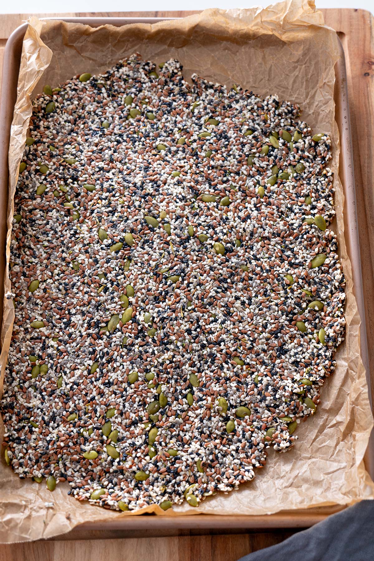 Spread of mixed seeds on baking paper ready to go into the oven.